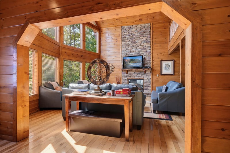 Sunlight streams through soaring windows into your cozy retreat, where vaulted ceilings and warm wood create an inviting space to unwind with views of the surrounding trees.