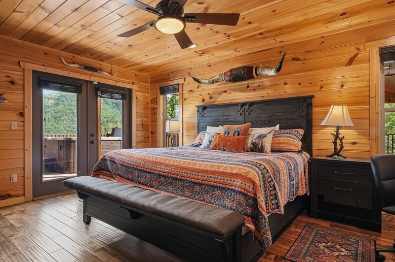 Unwind in your rusticchic bedroom with handcrafted wood walls, a plush king bed adorned with vibrant textiles, and private deck access inviting fresh mountain air into your peaceful retreat.