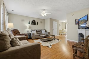 Sink into plush sectional seating by your cozy fireplace, where warm wood floors and rustic touches create the perfect retreat.