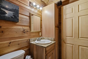Your private bathroom features rustic wood paneling, granite countertops, and warm lighting—offering a cozy retreat after a day of adventure.