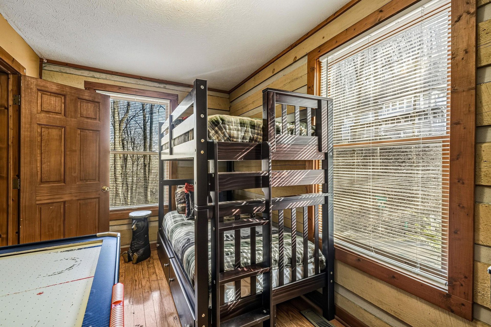 Your kids will love this cozy bunk room with rustic log walls and natural light streaming through the windows.