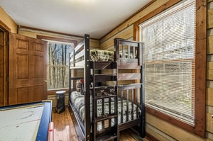 Your kids will love this cozy bunk room with rustic log walls and natural light streaming through the windows.