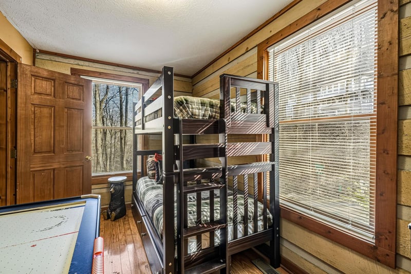Your kids will love this cozy bunk room with rustic log walls and natural light streaming through the windows.