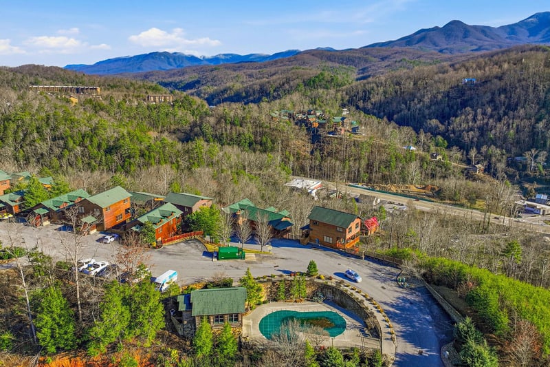Mountain resort featuring vacation cabins with green roofs, swimming pool, and scenic valley views.