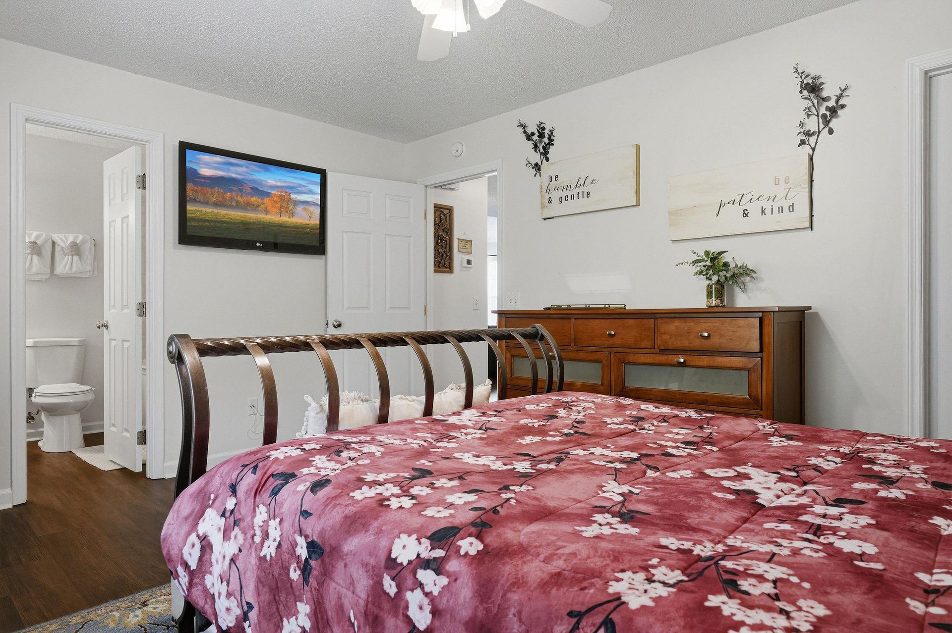 Relax in your cozy bedroom with a plush bed, mounted TV for entertainment, and an ensuite bathroom for your convenience. Warm touches like inspirational decor and natural light create a welcoming ret