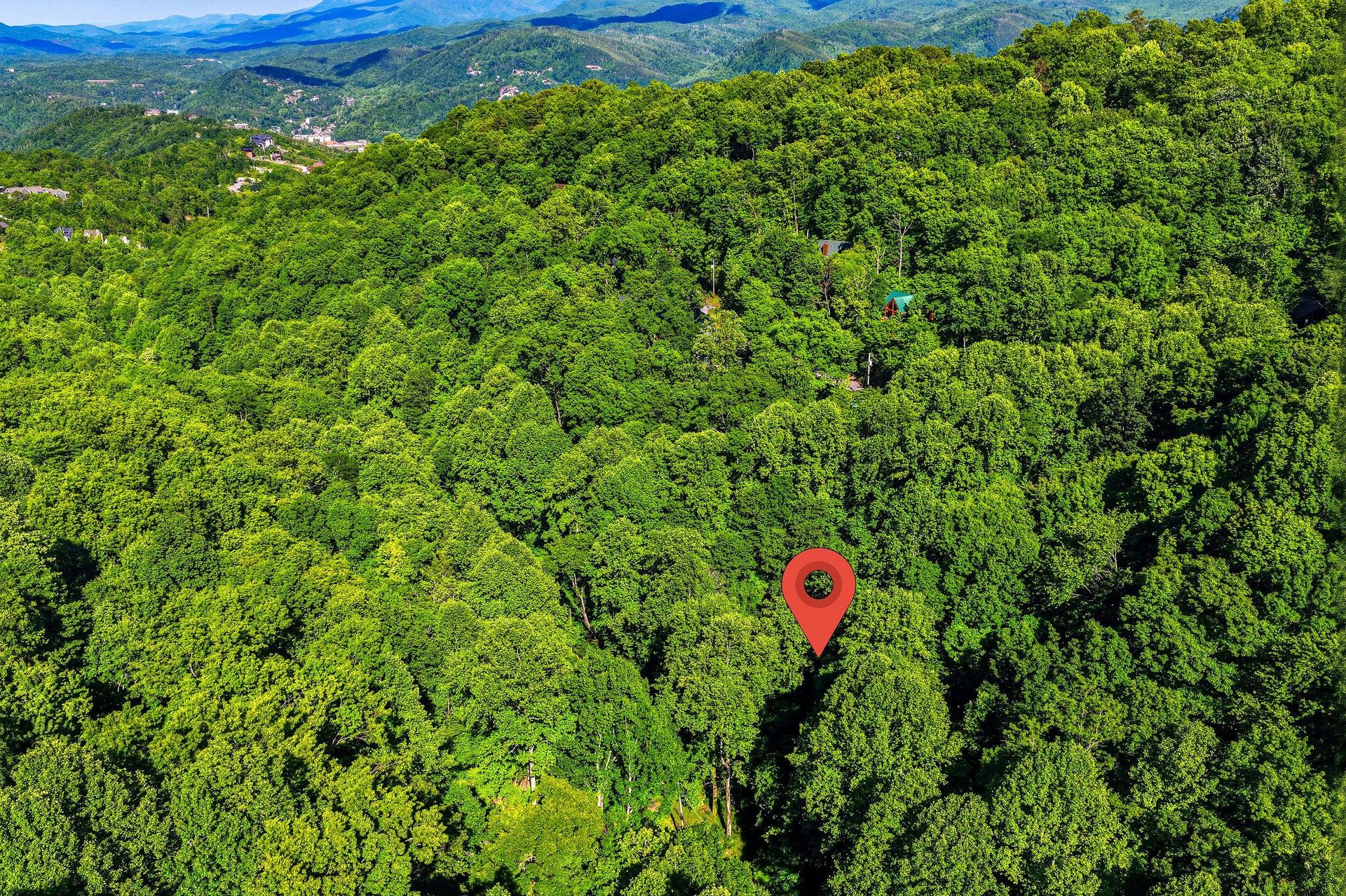 The property sits nestled in lush mountain forest, surrounded by rolling ridges and pristine wilderness as far as the eye can see.