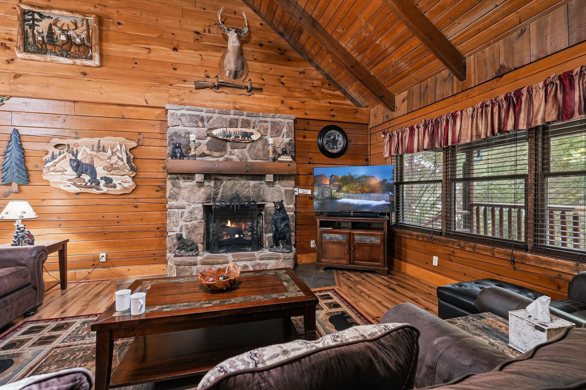 Sink into a cozy cabin retreat with knotty pine walls, a crackling stone fireplace, and serene wooded views right outside your window—your perfect hideaway.