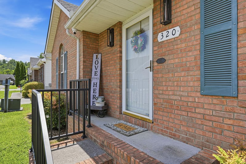 The propertys main entrance at 320 features warm red brick exteriors and a covered porch, welcoming guests to a quiet neighborhood setting surrounded by mature landscaping and treelined streets.