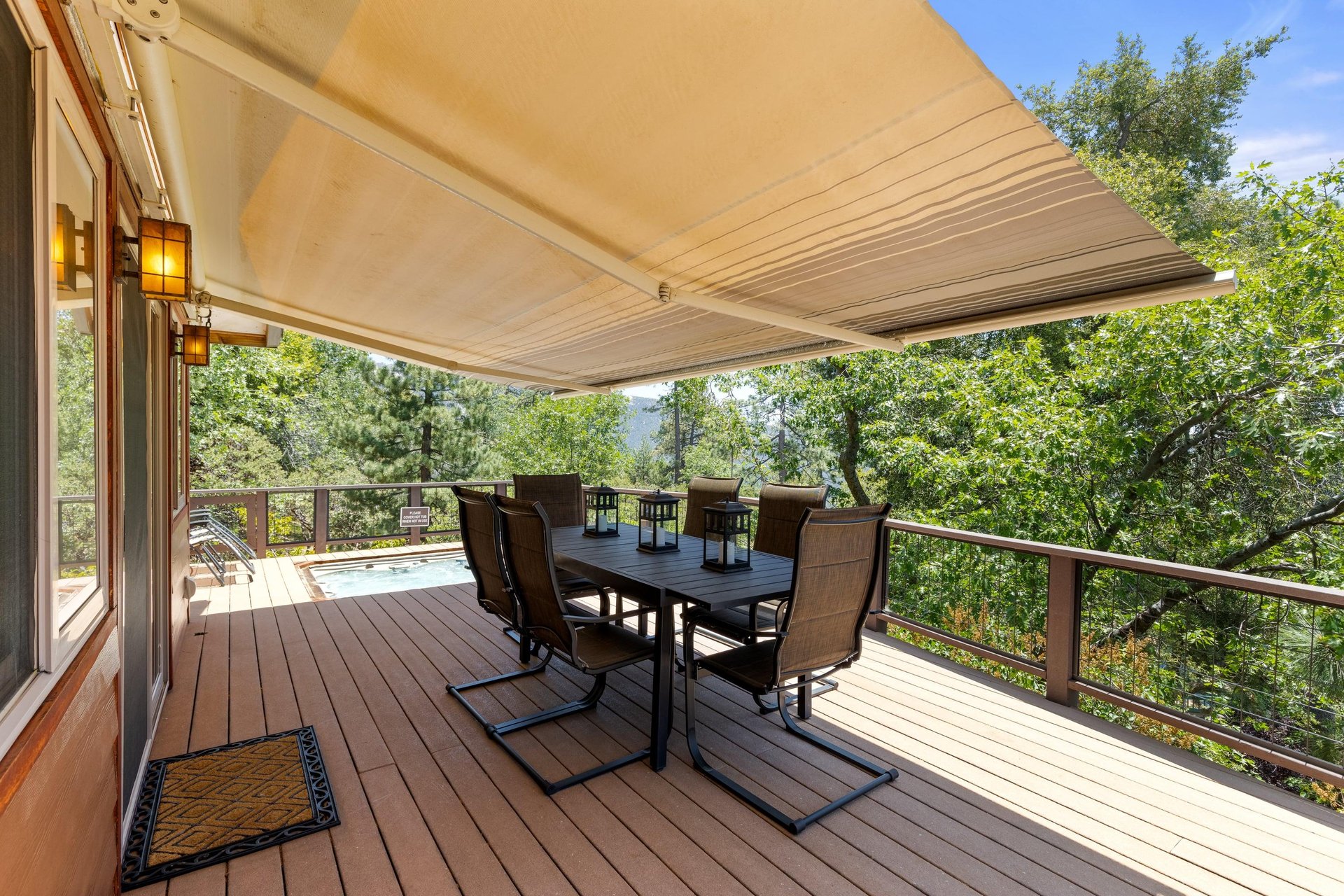 Back deck with retractable awning, outdoor seating, firepit, koi pond, fenced dog area, BBQ, and hot tub with mountain views.