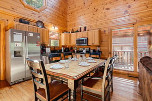 Gather around this inviting dining table in your fullyequipped cabin kitchen, where warm wood walls and natural light set the stage for memorable meals together.