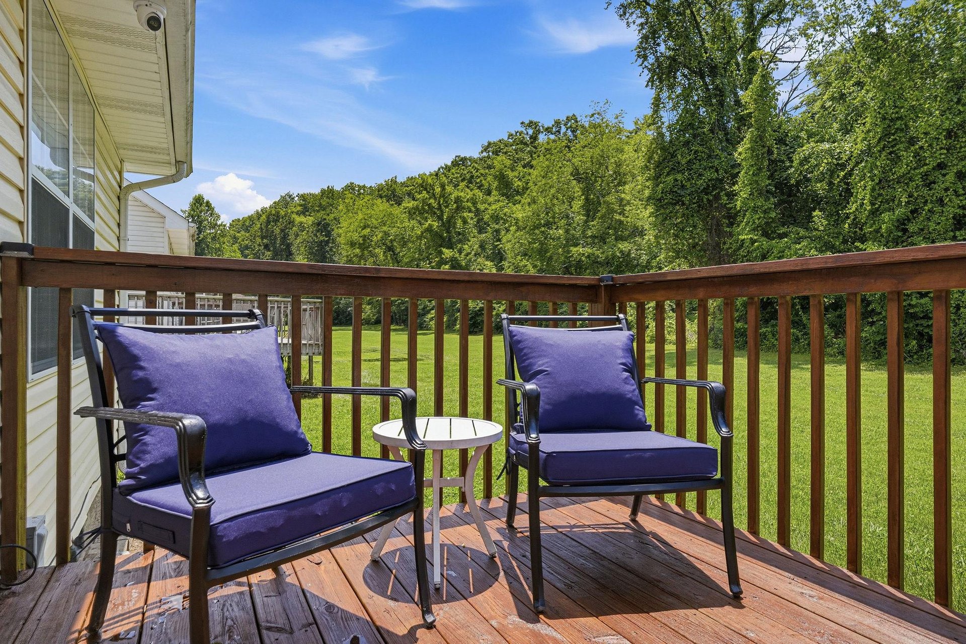 Peaceful deck with comfortable seating overlooking a green lawn and lush forest backdrop—perfect for morning coffee or unwinding after a day of exploring.