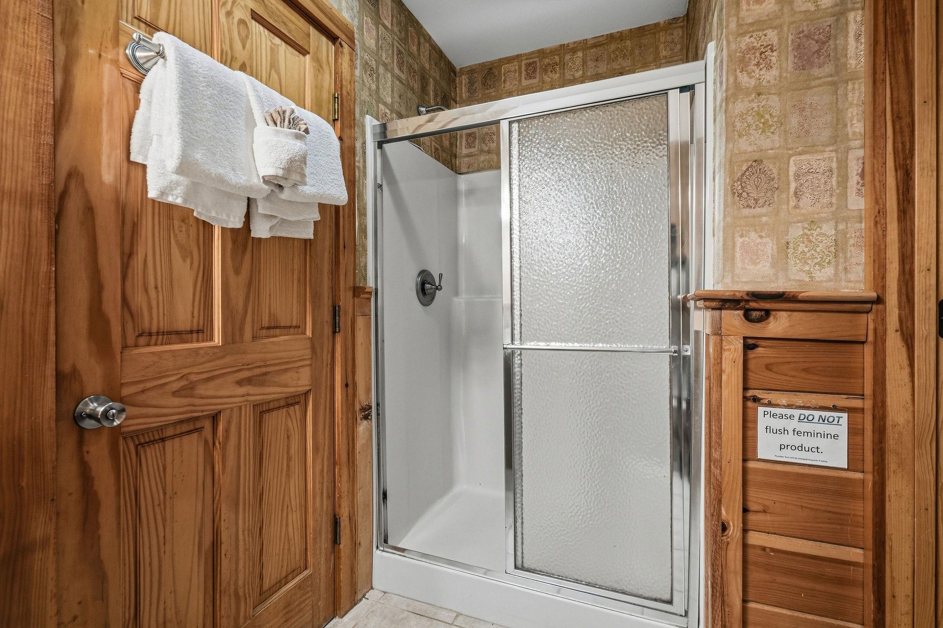 Step into your private bathroom featuring a spacious glassdoor shower, warm wood cabinetry, and fresh towels waiting for your arrival.