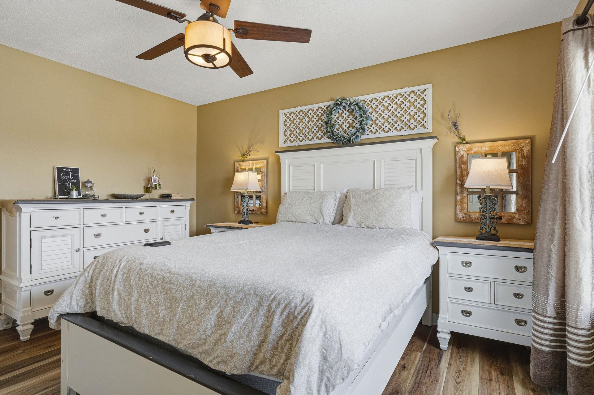 Your peaceful retreat awaits with a plush bed, calming décor, and gentle breezes from the ceiling fan overhead. Warm tones and soft lighting create a serene sanctuary for restful nights.