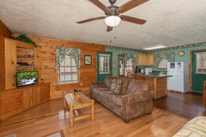 Living room with sofa, TV, and adjacent kitchen at Hideaway, a 1 bedroom cabin rental located in Pigeon Forge