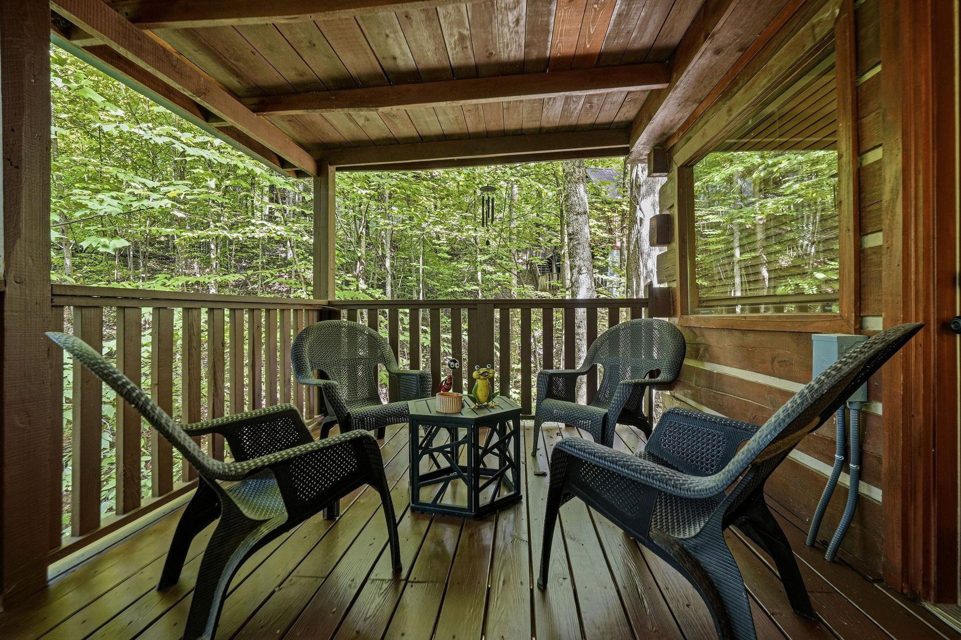 Your private covered deck invites you to unwind among the trees, where cozy seating and forest views create the perfect retreat for morning coffee or evening relaxation.