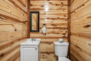Step into your rustic retreat bathroom, where warm wood walls and modern fixtures create the perfect cabin getaway atmosphere.