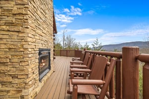 Fireplace, rocking chairs, and hot tub on a deck at Majestic Views, a 3 bedroom cabin rental located in Pigeon Forge