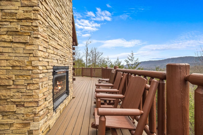 Fireplace, rocking chairs, and hot tub on a deck at Majestic Views, a 3 bedroom cabin rental located in Pigeon Forge