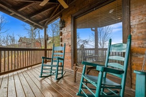 Sway gently in your rocking chairs on this charming covered porch, watching the world go by through peaceful trees and mountain views.