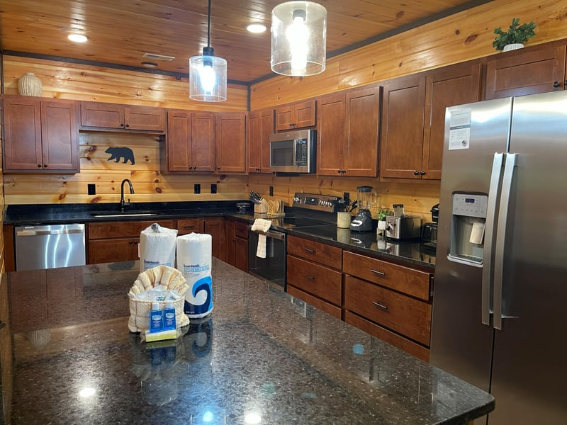 Step into a beautifully appointed kitchen with warm wood paneling, granite countertops, and stainless appliances—your perfect home base for cooking memorable meals during your stay.