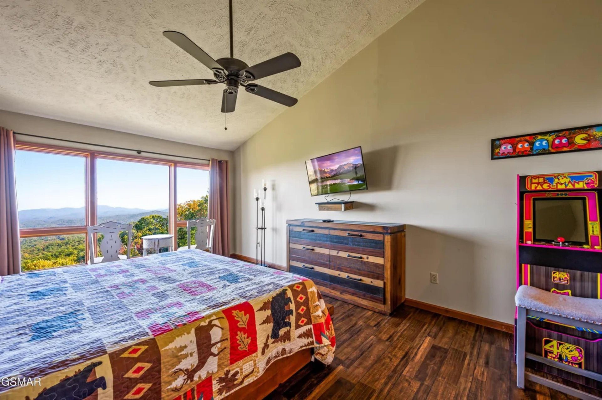Your bedroom combines comfort with entertainment, featuring mountain views, a vintage arcade game, and all the amenities for a perfect retreat.