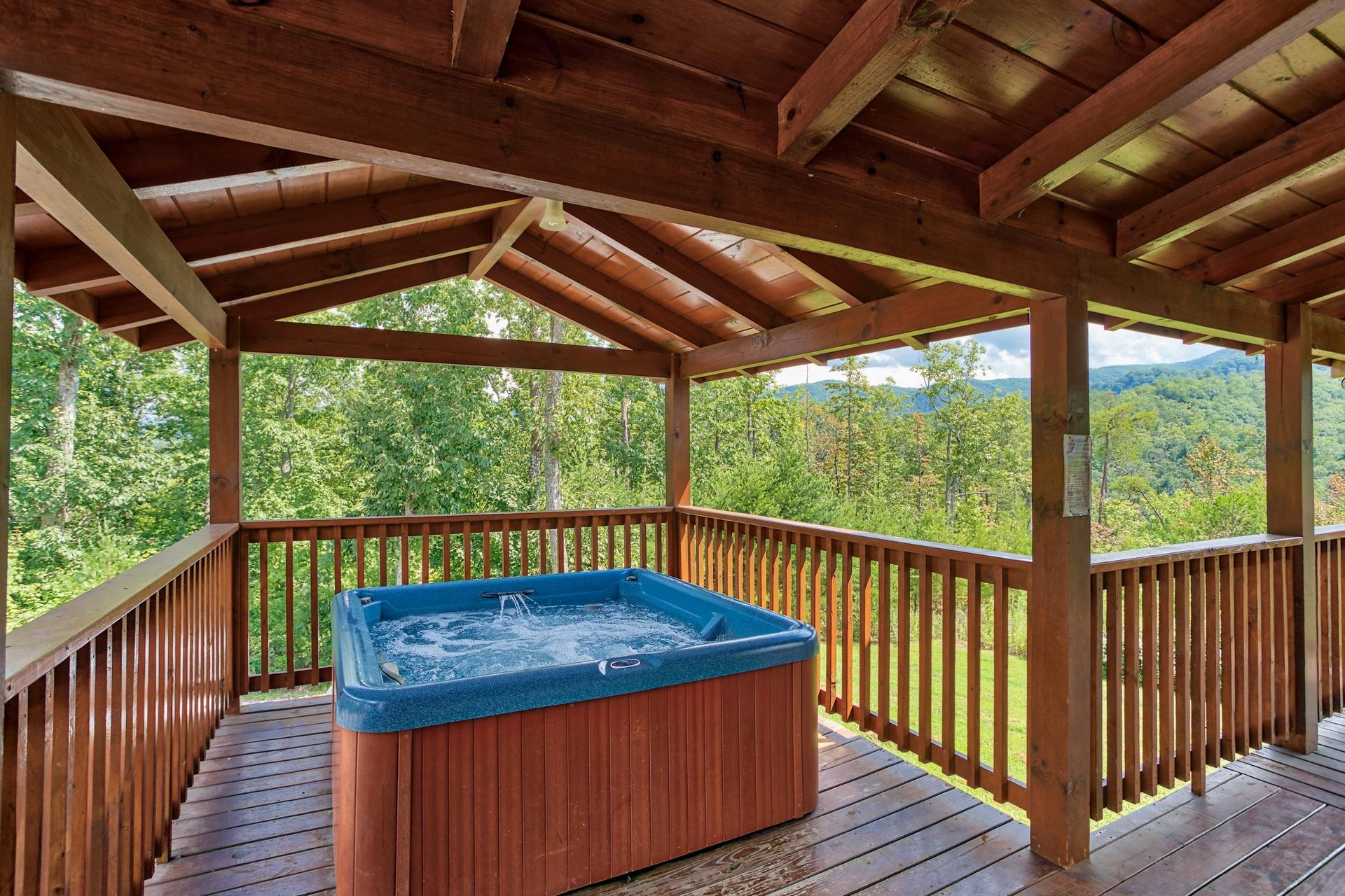 Hot tub on a covered deck at Four Seasons Lodge, a 3bedroom cabin rental located in Pigeon Forge