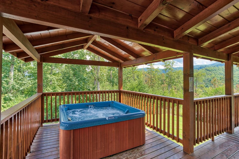 Hot tub on a covered deck at Four Seasons Lodge, a 3bedroom cabin rental located in Pigeon Forge