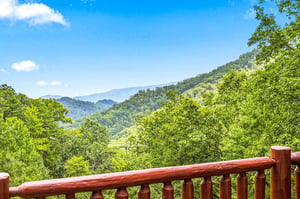 Sweeping mountain vistas stretch across lush green peaks, framed by a charming wooden railing that invites quiet moments of natural beauty.
