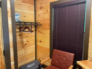 Warm wooden walls and a convenient clothing rack provide a cozy spot to settle in and make yourself at home.
