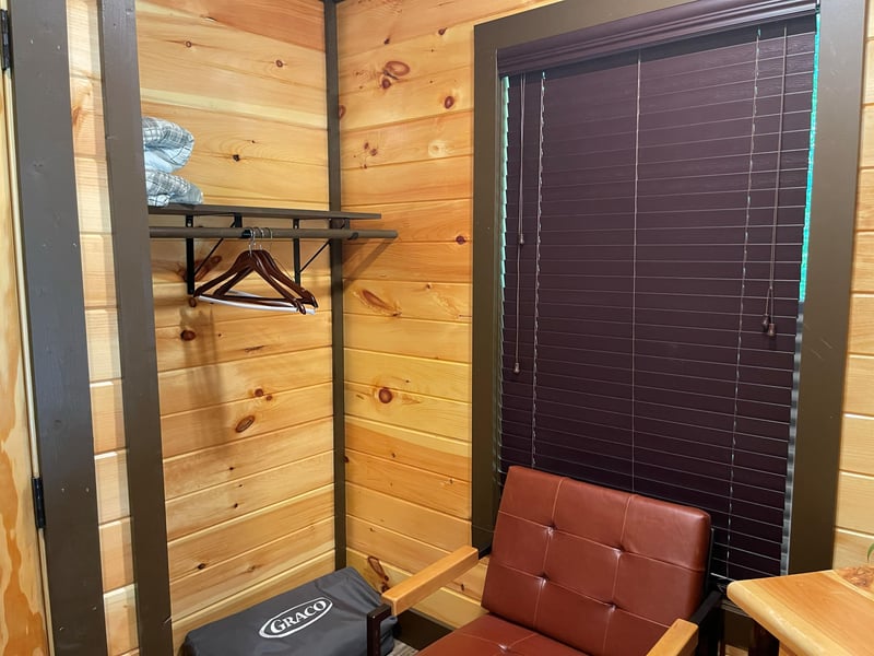Warm wooden walls and a convenient clothing rack provide a cozy spot to settle in and make yourself at home.