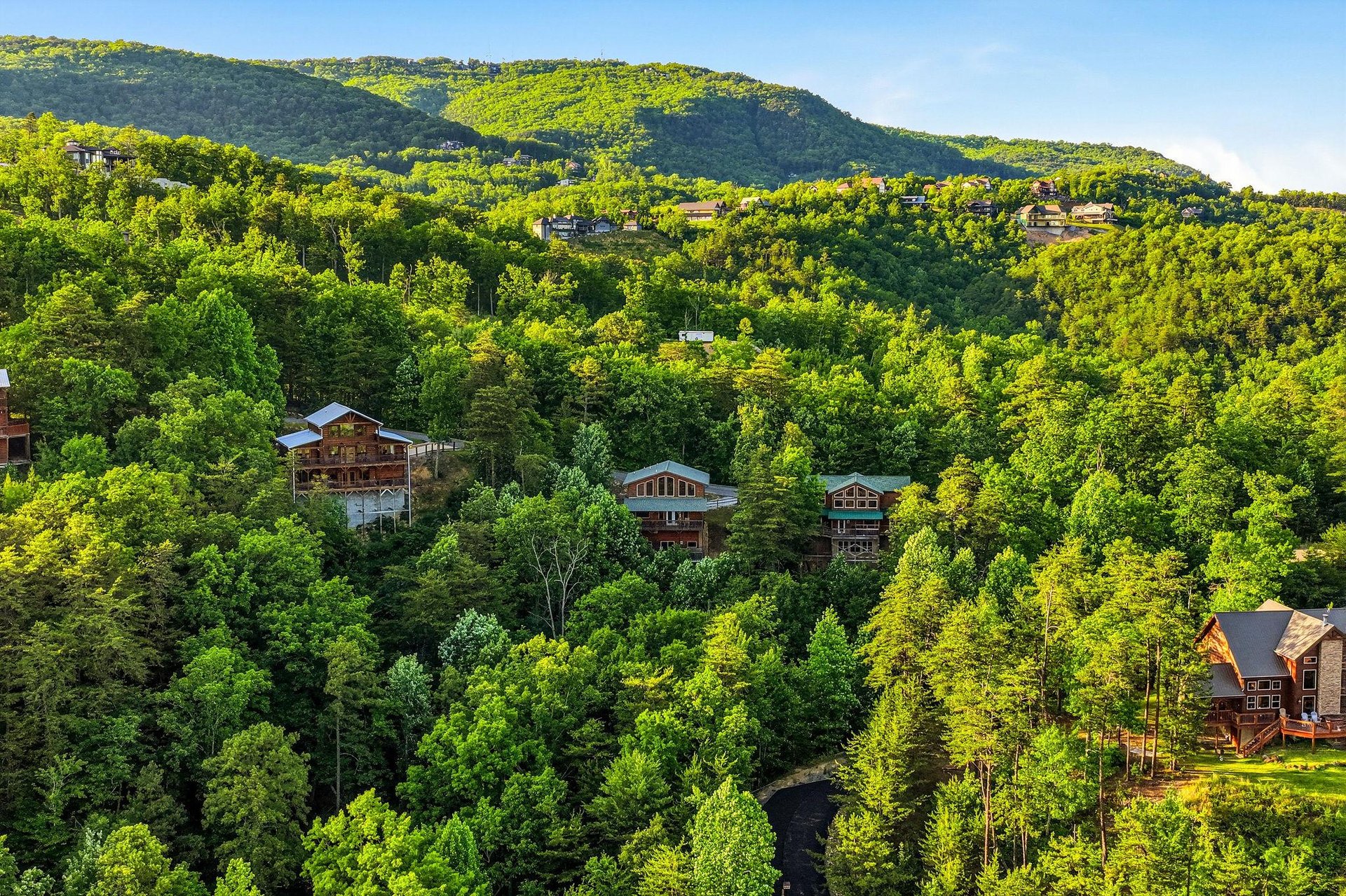 Nestled in lush mountain forest, this property offers peaceful seclusion and natural beauty, with nearby homes dotting the vibrant green hillside beneath clear blue skies.