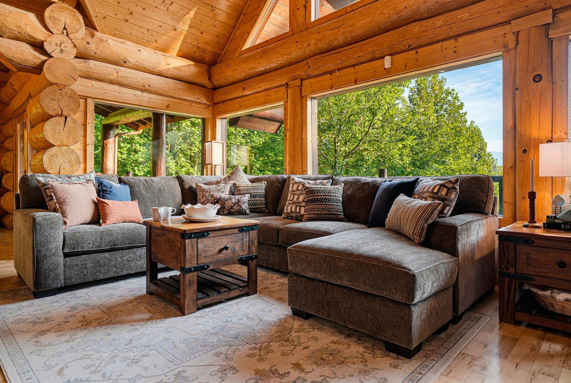 Sink into plush seating surrounded by warm log walls and gaze out at lush greenery framing your peaceful forest retreat.