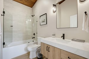 Refresh in your modern, spalike bathroom with a sleek glassenclosed tub and spacious vanity, all under warm wood beam ceilings.