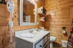 Step into your cozy cabin bathroom, where warm wood walls meet modern comfort. Fresh towels await you, woven storage adds rustic charm, and the space is thoughtfully designed for your mountain getaway