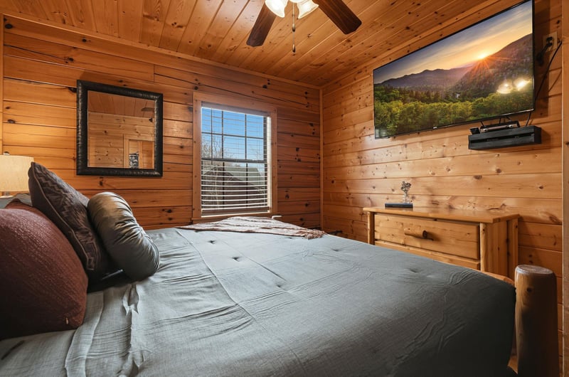 Drift off to sleep in this cozy log cabin bedroom, where warm wood surrounds you and nature views await outside your window.