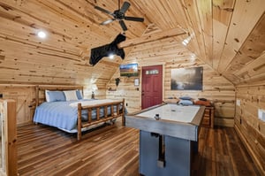 Your cozy cabin loft features exposed beams, rustic wood walls, and a ceiling fan overhead. Challenge your crew to air hockey before retiring to the comfy bed.