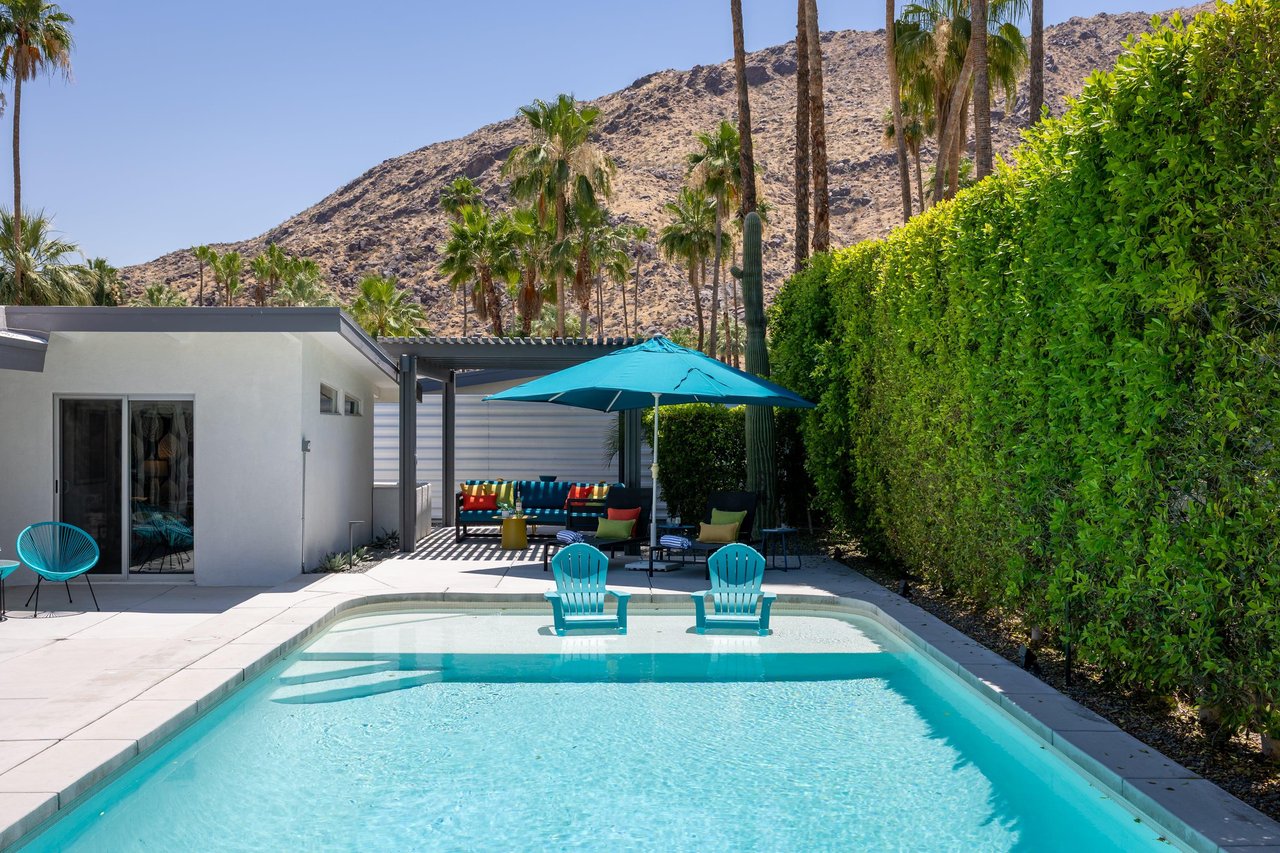 View of pergola with shaded outdoor seating and shallow end in pool.
