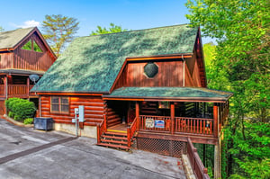 This charming log cabin retreat offers authentic mountain charm with its rustic wood exterior and wraparound deck, nestled among towering trees.