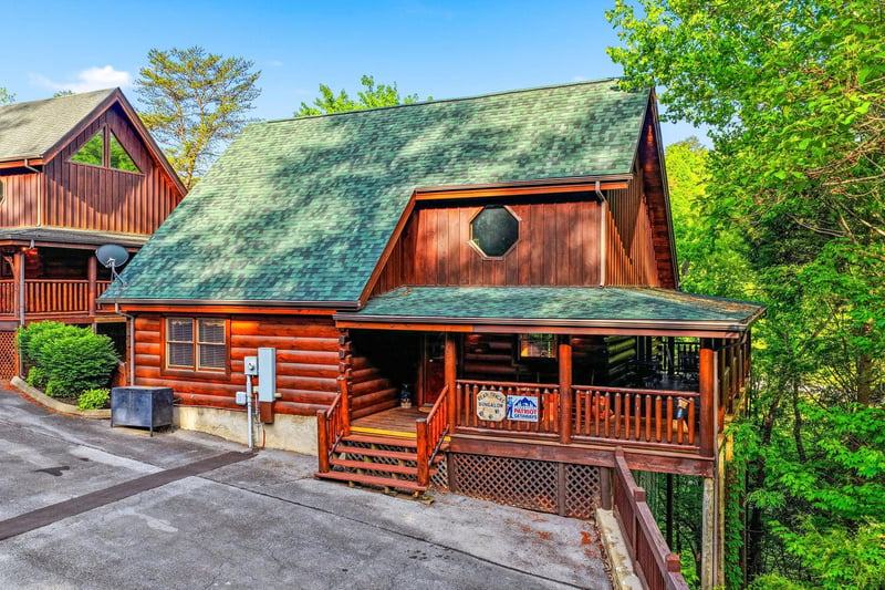 This charming log cabin retreat offers authentic mountain charm with its rustic wood exterior and wraparound deck, nestled among towering trees.
