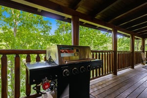 Fire up your favorite meals on this covered deck with a premium gas grill, surrounded by lush greenery for the perfect outdoor dining experience.