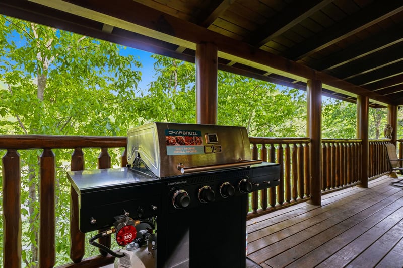 Fire up your favorite meals on this covered deck with a premium gas grill, surrounded by lush greenery for the perfect outdoor dining experience.