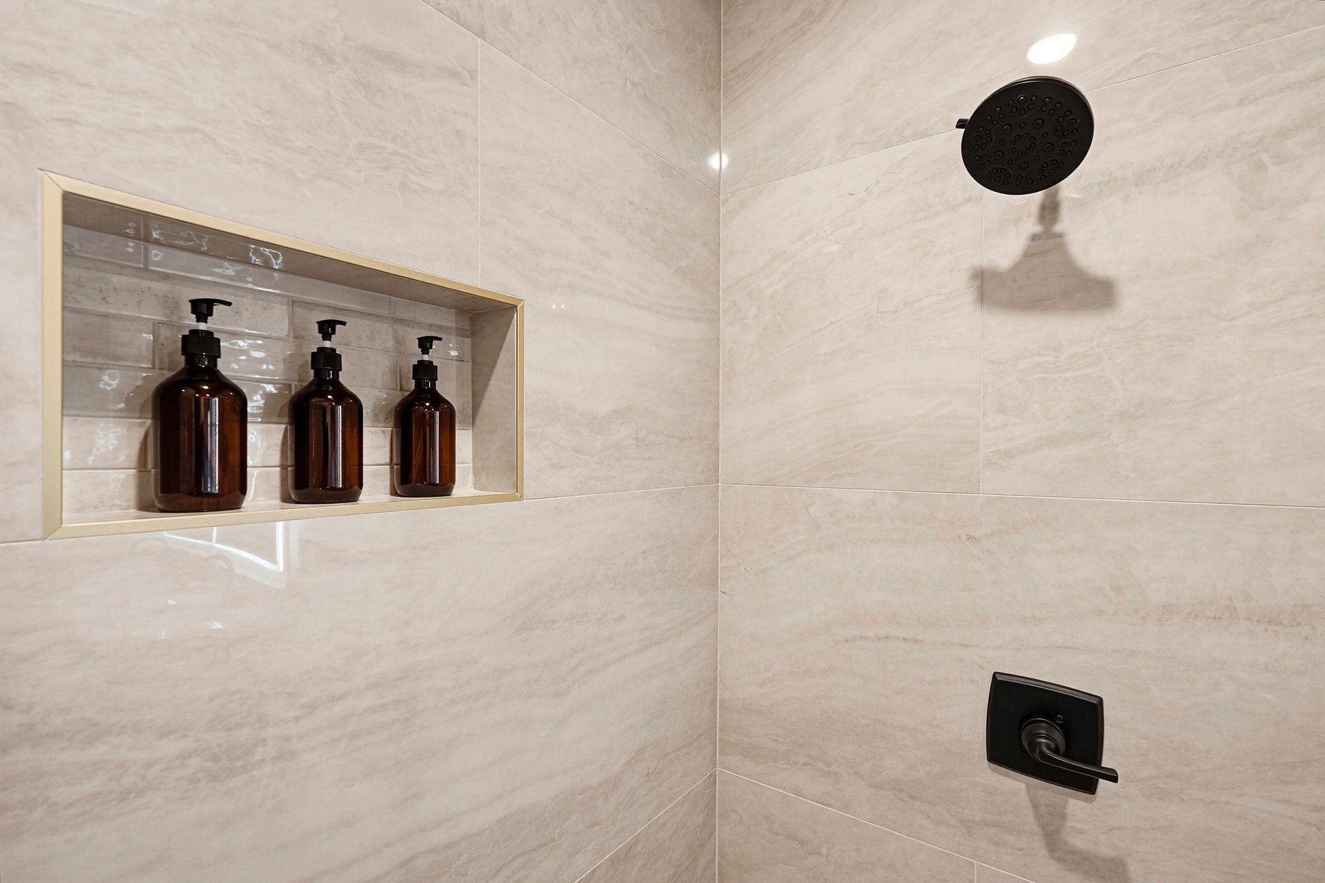 Step into your beautifully appointed shower with elegant marblestyle tile, matte black fixtures, and premium toiletries ready for your comfort.