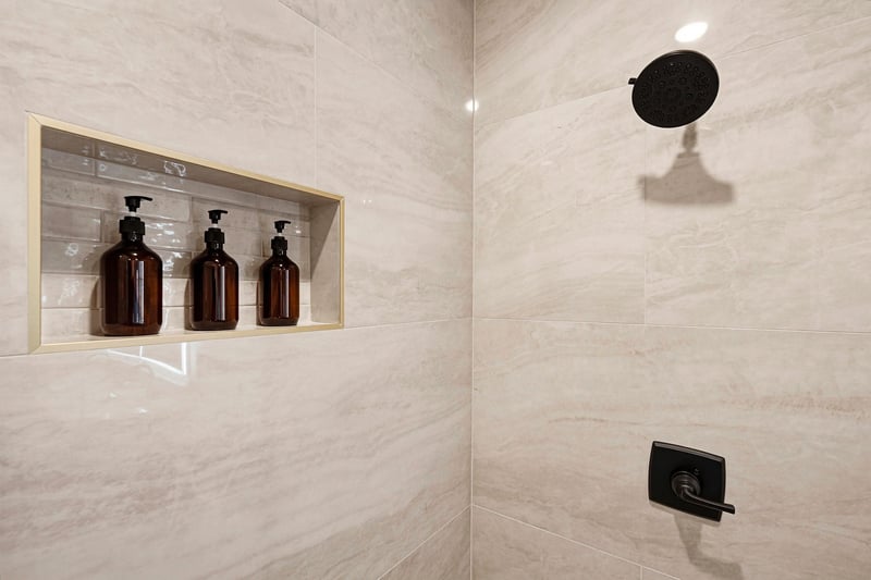 Step into your beautifully appointed shower with elegant marblestyle tile, matte black fixtures, and premium toiletries ready for your comfort.