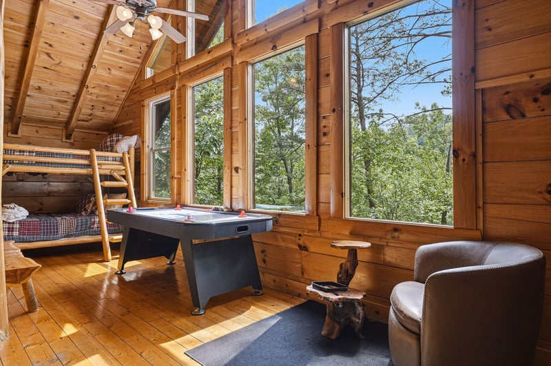 Gather with loved ones in this sunlit game room, where bunk beds and an air hockey table set the stage for friendly competition and laughter beneath soaring wood ceilings.