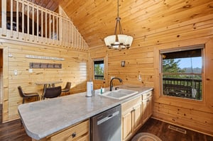 Embrace rustic charm in this stunning log cabin kitchen with soaring ceilings and forest views from your dining spot.