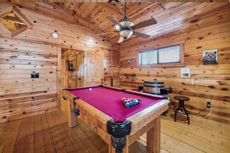 Challenge friends to a game of pool in your private rustic game room, complete with warm wood walls and cozy cabin atmosphere.