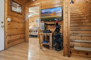 Cozy up in your rustic log cabin living area with warm wood walls, a large TV for movie nights, and charming seasonal touches.