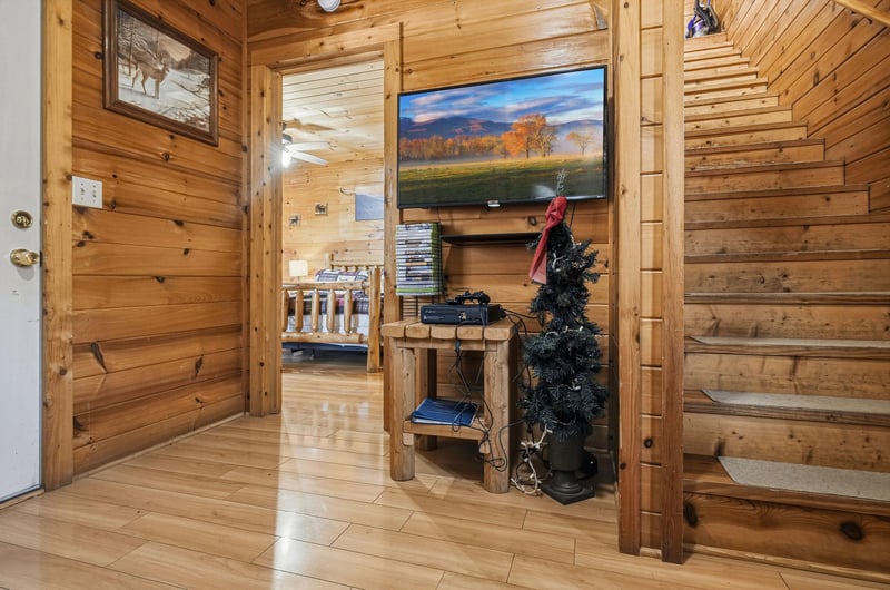 Cozy up in your rustic log cabin living area with warm wood walls, a large TV for movie nights, and charming seasonal touches.
