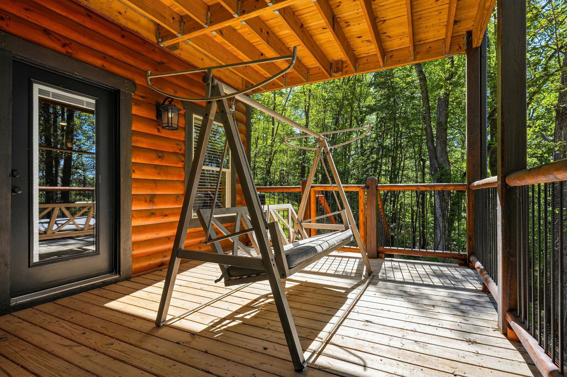 Sway gently on your private deck swing surrounded by towering trees and dappled sunlight filtering through the forest canopy.