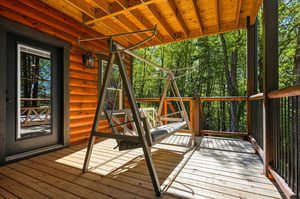 Sway gently on your private deck swing surrounded by towering trees and dappled sunlight filtering through the forest canopy.